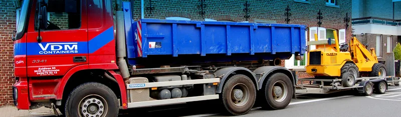 Rode VDM Containers-vrachtwagen met haakarm draagt een blauwe afzetcontainer en sleept een aanhanger met een gele compacte wiellader.